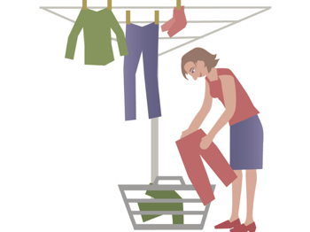 Een vrouw hangt de was op aan een droogmolen